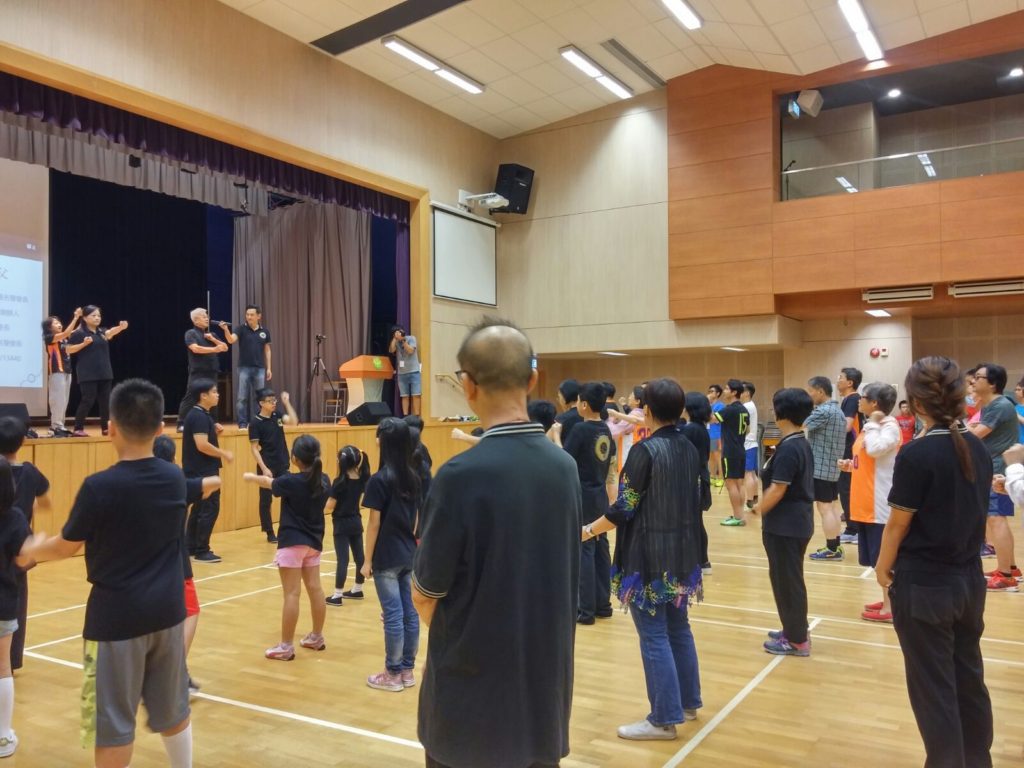 在中學會堂之中，梁錦棠師父與眾弟子教授參與者詠春基本拳法